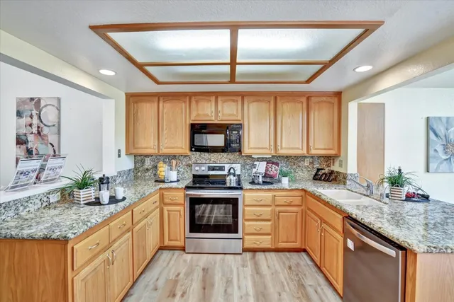 a kitchen with stainless steel appliances granite countertop a sink stove cabinets and wooden floor