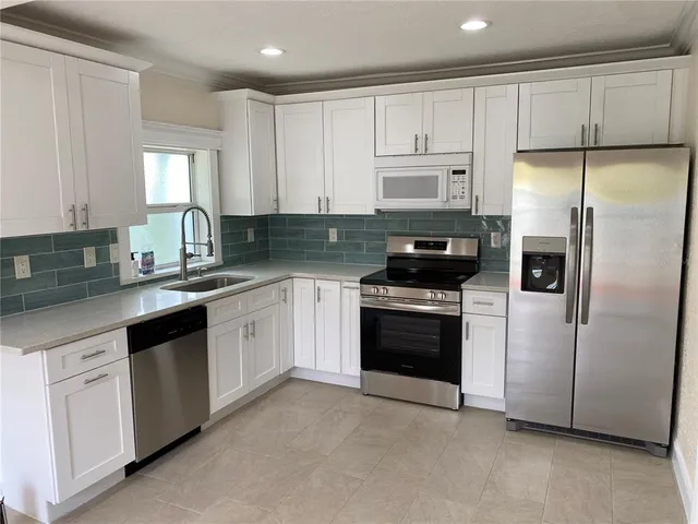 a kitchen with white cabinets and stainless steel appliances