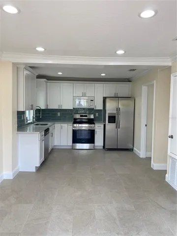 a large kitchen with stainless steel appliances granite countertop a refrigerator and a stove top oven