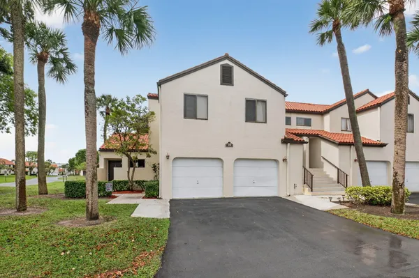 a view of a house with a yard and palm trees