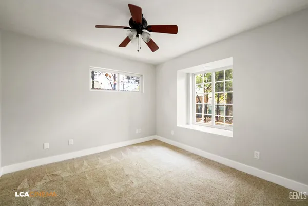 an empty room with ceiling fan and windows
