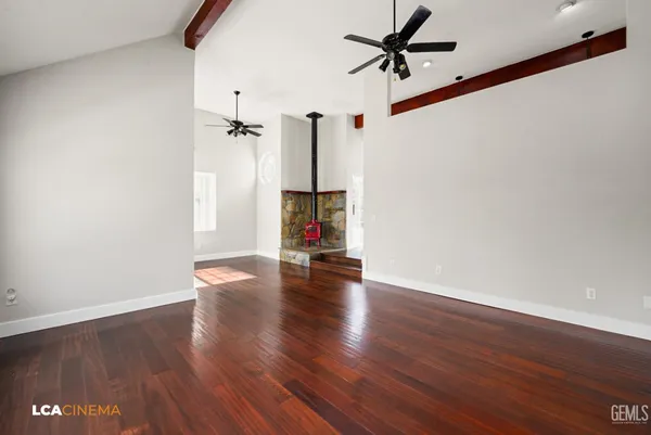 a view of empty room with wooden floor and ceiling fan