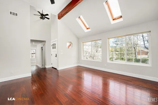 a view of an empty room with a window and wooden floor