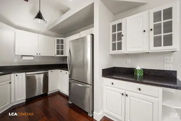 a kitchen with stainless steel appliances granite countertop a refrigerator a sink and white cabinets