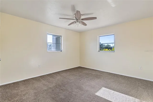 an empty room with a window and a ceiling fan