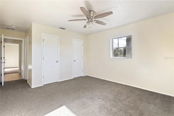 an empty room with a ceiling fan and a window