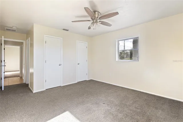 an empty room with a ceiling fan and a window