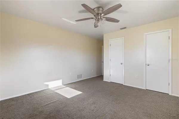 an empty room with a ceiling fan and a window
