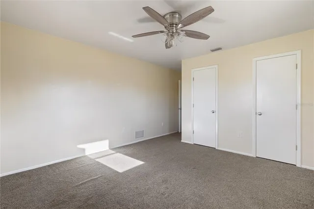 an empty room with a ceiling fan and a window