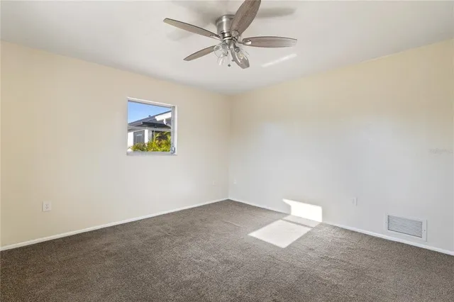 an empty room with a window and a ceiling fan