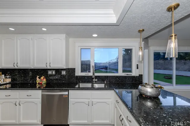 a kitchen with stainless steel appliances granite countertop a sink a stove and cabinets