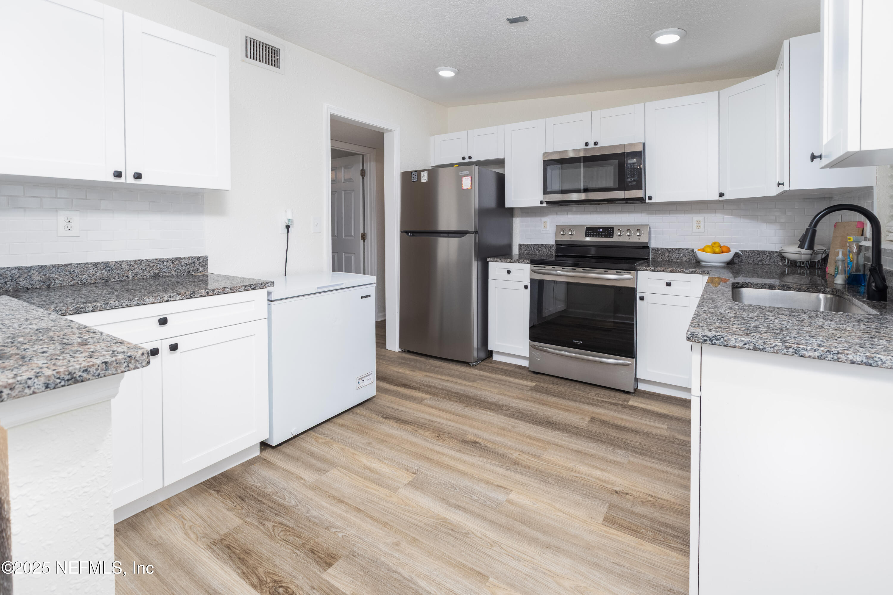 3165 Victoria Park Road Jacksonville, FL 32216 - Photo 5 of 22 a kitchen with granite countertop a sink stainless steel appliances and white cabinets