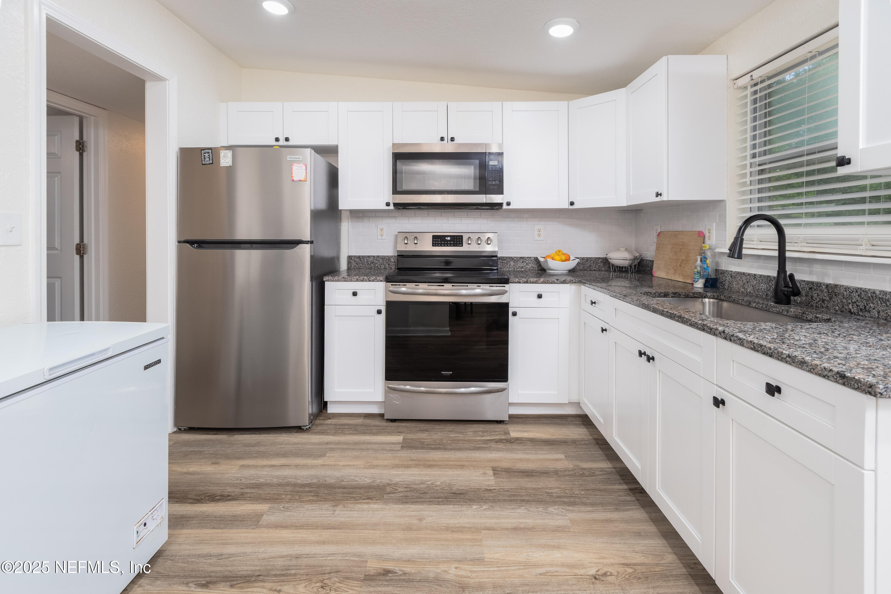 3165 Victoria Park Road Jacksonville, FL 32216 - Photo 7 of 22 a kitchen with granite countertop a refrigerator stove and white cabinets