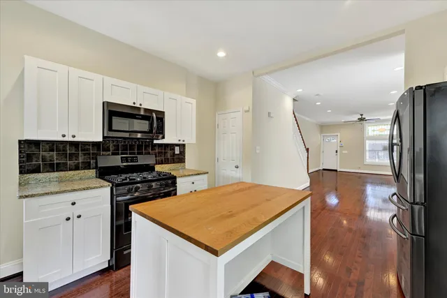 a kitchen with stainless steel appliances a stove top oven a sink dishwasher and a refrigerator with wooden floor