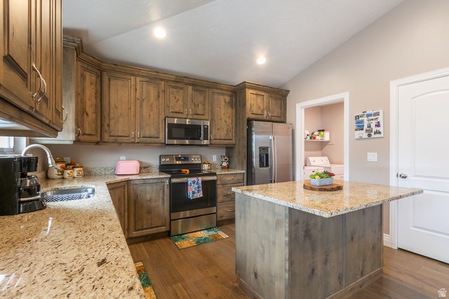 1228 North Providence Way Tooele, UT 84074 - Photo 9 of 28 Kitchen featuring wood-finish cabinetry, light-toned granite countertops, stainless steel appliances, a center island with granite surface, and wood-finish flooring