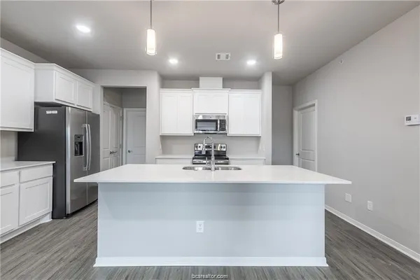 a view of a kitchen with kitchen island a sink stainless steel appliances and cabinets
