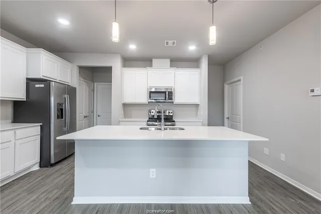 a view of a kitchen with kitchen island a sink stainless steel appliances and cabinets