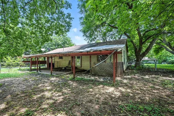 a backyard of a house with table and chairs under an umbrella