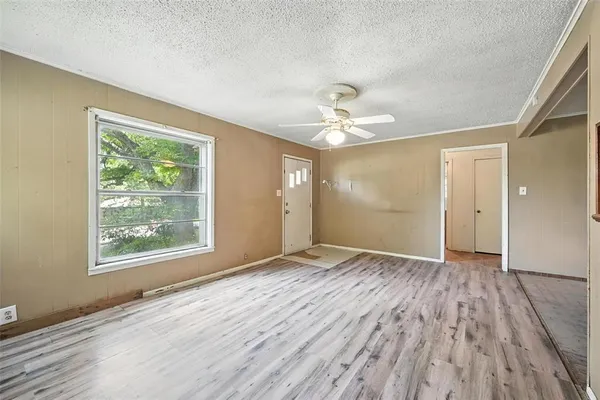 an empty room with wooden floor chandelier and windows