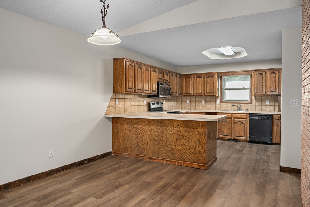 3022 Dow Jones Road Alma, AR 72921 - Photo 8 of 34 Kitchen featuring brown cabinetry, light countertops, decorative light fixtures, and dishwasher