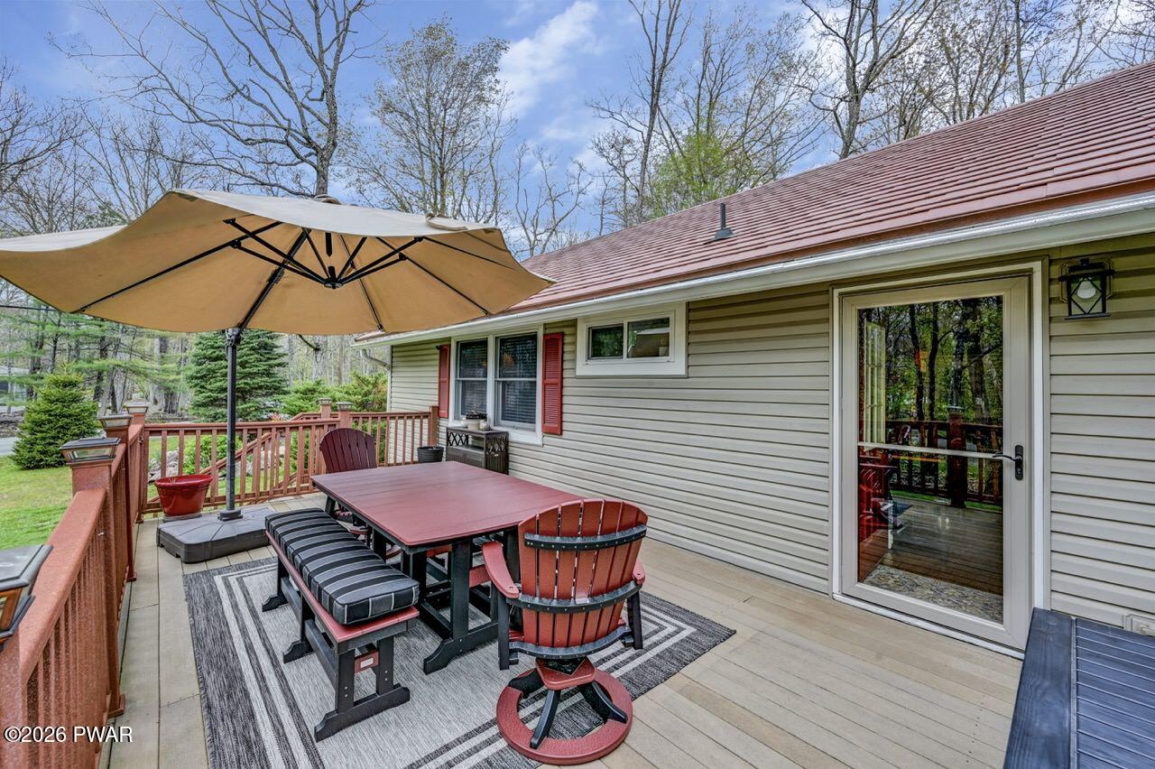 103 Forest Drive Hawley, PA 18428 - Photo 63 of 85 a patio with wooden floor a yard a table and chairs