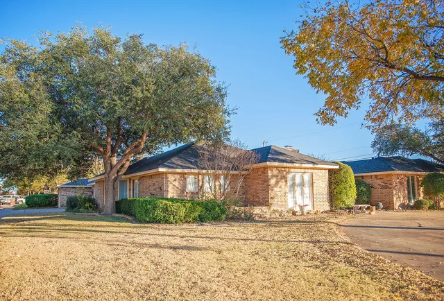 a view of a house with a yard and large trees