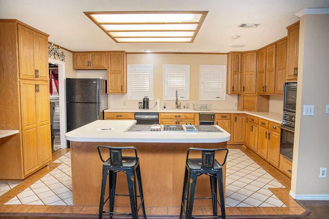 a kitchen with stainless steel appliances granite countertop a dining table chairs and a refrigerator
