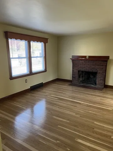 an empty room with wooden floor fireplace and windows