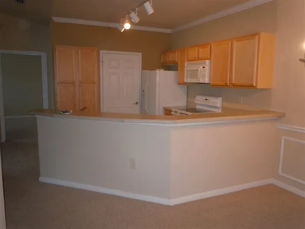 a view of a refrigerator a sink and cabinets
