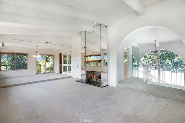 a view of an empty room with a window and a kitchen