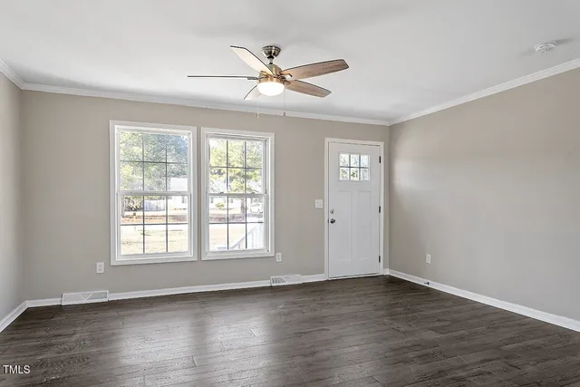 a view of an empty room with wooden floor and a window