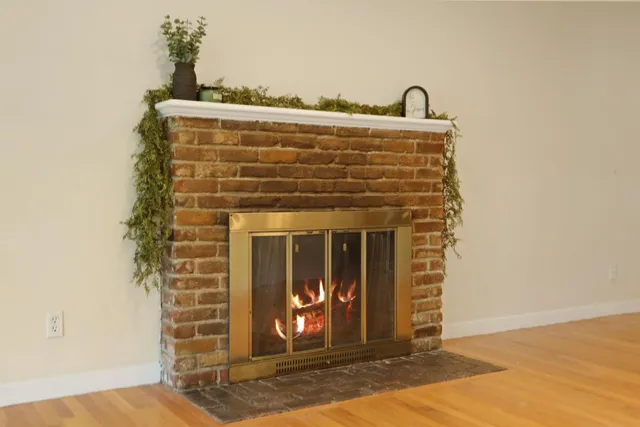 a view of an empty room with wooden floor fire place