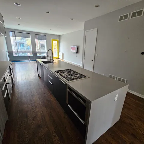 a kitchen with stainless steel appliances granite countertop a stove a sink dishwasher a refrigerator and wooden floor