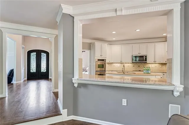 a view of a kitchen with kitchen island stainless steel appliances wooden floor and refrigerator