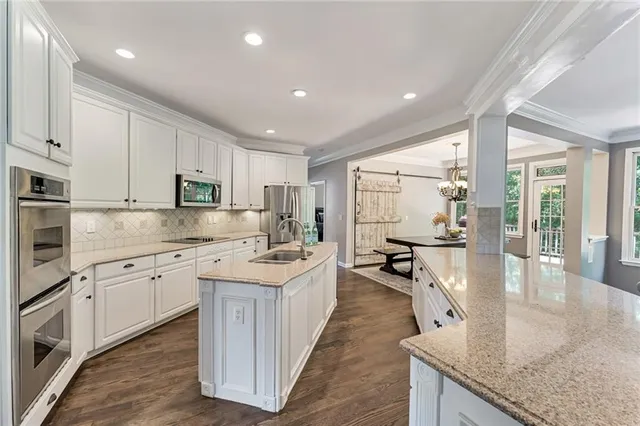 a kitchen with stainless steel appliances granite countertop a stove top oven a sink a dining table and chairs