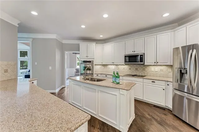 a kitchen with stainless steel appliances granite countertop a refrigerator sink stove microwave and cabinets