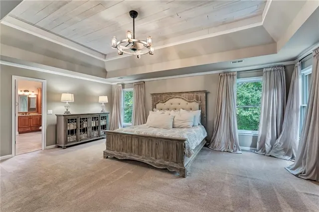 a spacious bedroom with a bed a chandelier and balcony