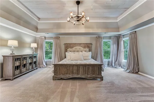 a spacious bedroom with a balcony a bed and a chandelier