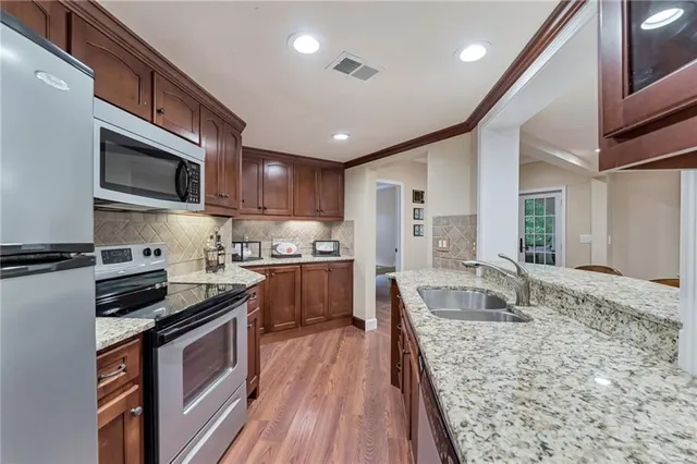 a kitchen with stainless steel appliances granite countertop wooden cabinets a stove top oven a sink and dishwasher