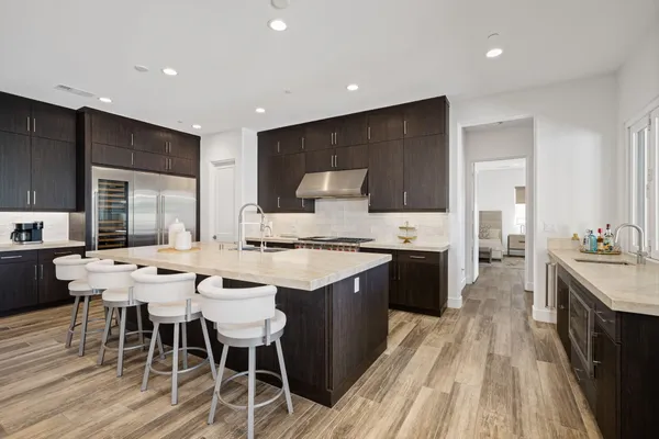a large kitchen with a large counter top a sink stainless steel appliances and cabinets