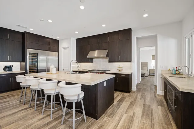 a large kitchen with a large counter top a sink stainless steel appliances and cabinets