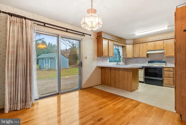 a large kitchen with stainless steel appliances granite countertop a refrigerator a sink dishwasher a oven and a dining table with wooden floor