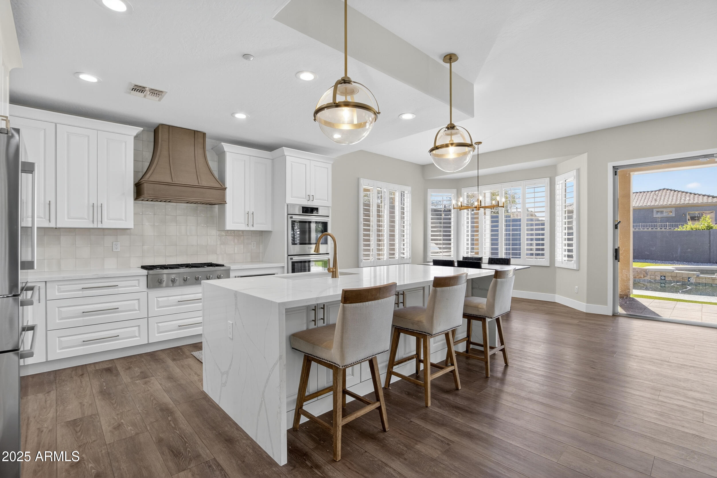 10587 East Sheena Drive Scottsdale, AZ 85255 - Photo 11 of 56 a kitchen with stainless steel appliances granite countertop a stove a refrigerator a kitchen island a dining table and chairs with wooden floor
