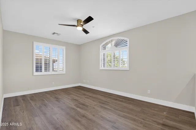 a view of an empty room with wooden floor a fireplace and a window
