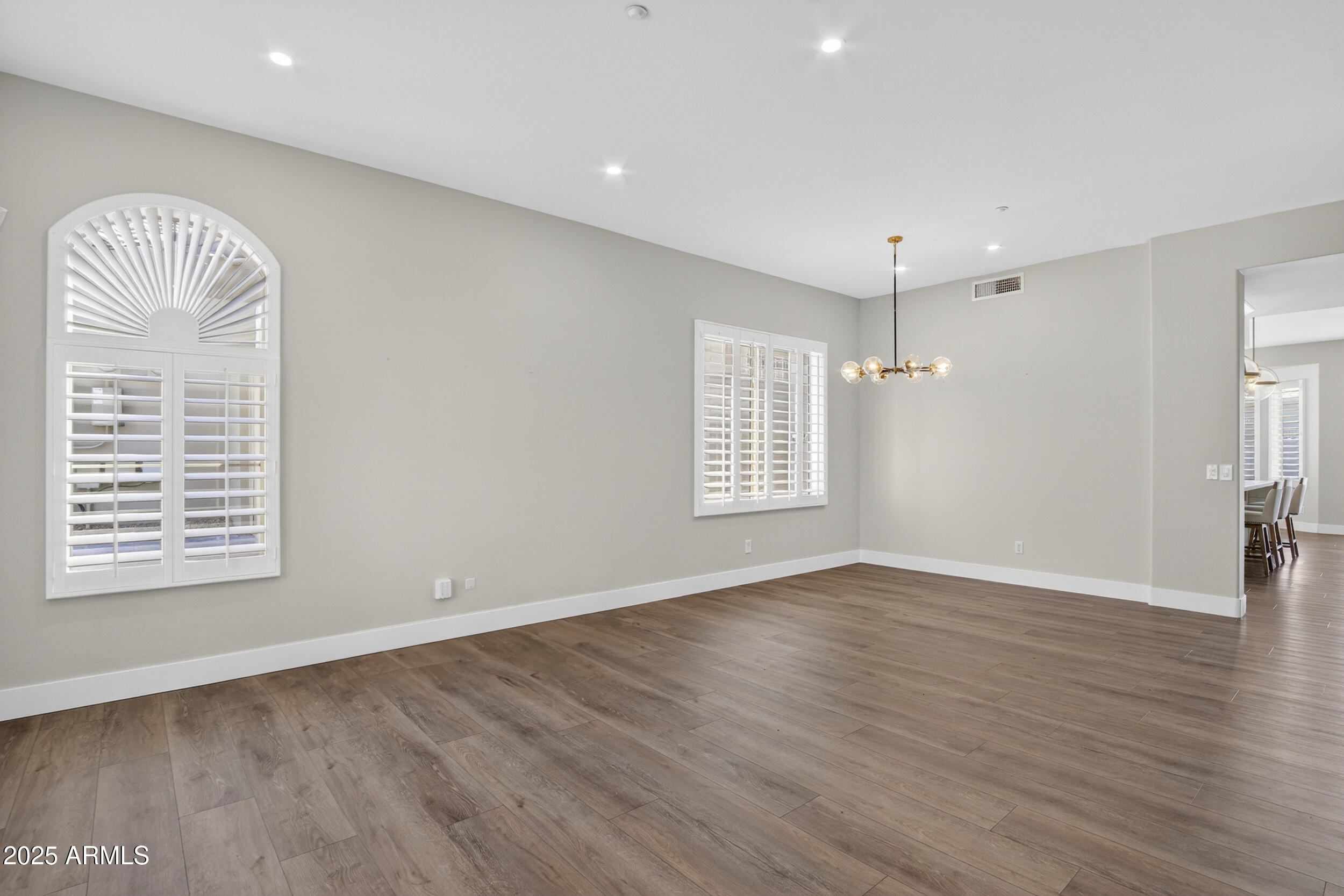 10587 East Sheena Drive Scottsdale, AZ 85255 - Photo 7 of 56 an empty room with wooden floor chandelier and windows