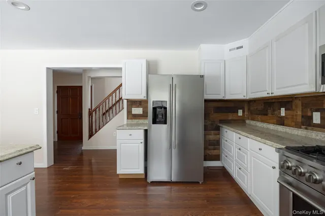 a kitchen with stainless steel appliances granite countertop a refrigerator a stove and a sink