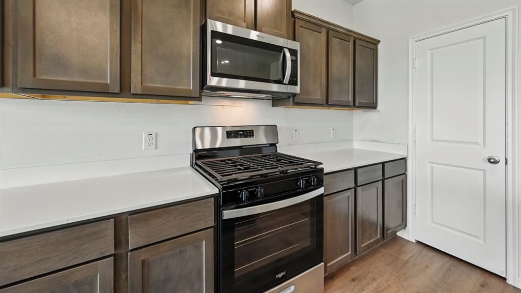 4607 Enclave Drive Sanger, TX 76266 - Photo 22 of 34 a kitchen with stainless steel appliances granite countertop white cabinets and a stove top oven