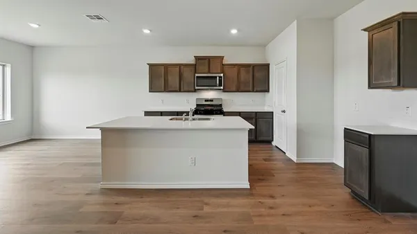 a room with kitchen island stainless steel appliances a sink wooden floor and window