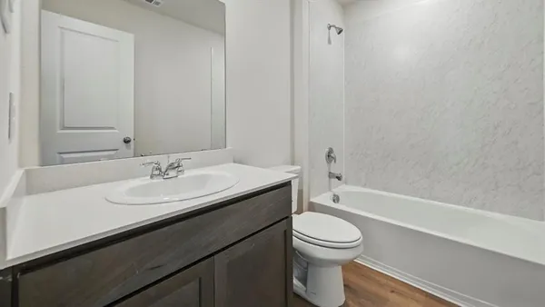 a bathroom with a granite countertop sink toilet a mirror and bathtub