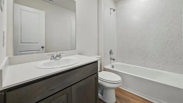 a bathroom with a granite countertop sink toilet a mirror and bathtub